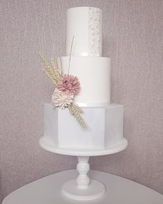 a three tiered white cake with pink flowers on top