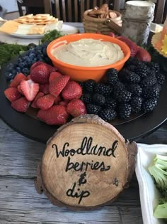 there is a platter with berries and dip on the table next to other foods