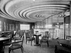 an old black and white photo of a restaurant with round tables, chairs and piano