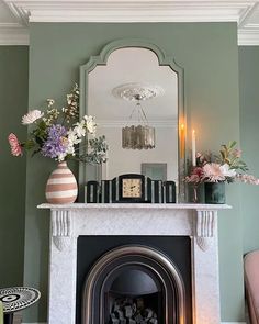 a living room with a fireplace, mirror and vases on top of the mantle