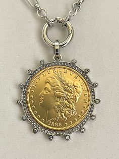 Beautiful reproduction vintage Gold coin pendant, Morgan Peace Dollar coin in a silver bezel with cubic zirconia stones. The bale attached to the coin is also encrusted with CZ stones. The coin is 22k gold plated and elegantly hangs from a multi link Rhodium plated brass chain and a spring lock CZ clasp The spring lock closure not only makes it easy to open and close the necklace for those with difficulty but adds to the creativity of the jewelry piece. Will enhance any outfit. Jeans to the litt Collectible Metal Jewelry With Coin Pendant, Diamond Coin Pendant Jewelry, White Gold Necklace With Coin Pendant, Silver Medallion Necklace With Chain, Luxury Silver Medallion Necklace, Elegant Coin Medallion Necklace With Chain, Elegant Hallmarked Coin Necklace, Gold Diamond Round Coin Necklace, Diamond Coin Pendant Medallion Jewelry