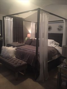 a bedroom with four poster bed and white curtains