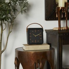 a clock sitting on top of a table next to a potted plant and candle