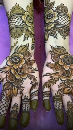 two hands with henna tattoos on them, one is showing the intricate design and the other has flowers