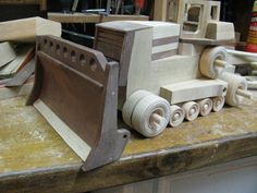 a wooden toy bulldozer sitting on top of a workbench in a shop