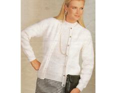 a woman wearing a white sweater and checkered skirt is holding a black handbag