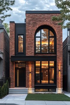 a modern brick house with large windows and black shutters on the front, surrounded by grass