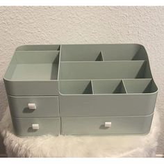 a gray drawer with six drawers on top of white furnishing and a wall in the background