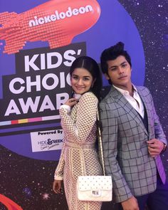 two people standing next to each other in front of a purple wall with the words kids's choice awards written on it