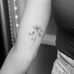 a black and white photo of a woman's arm with a flower tattoo on it