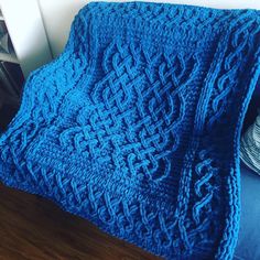 a blue knitted blanket sitting on top of a wooden floor next to a window