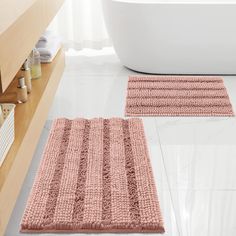 two bathroom rugs on the floor in front of a bathtub