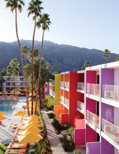 an outdoor swimming pool with colorful buildings and palm trees