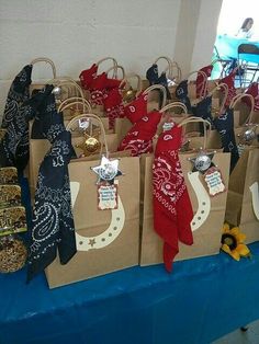 many bags are lined up on a blue table cloth and some have cowboy themed decorations