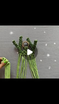 someone is crocheting green yarn with their hands and fingers to make an ornament