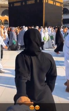 a person in a black outfit is sitting on the ground and people are standing around