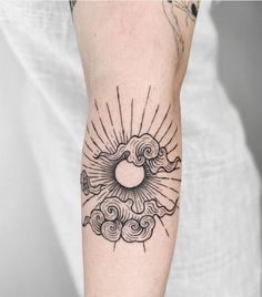 a person with a sun and clouds tattoo on their arm