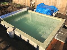 an empty pool in the middle of a backyard with a blue tarp over it