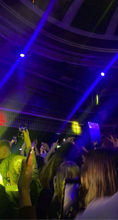 a group of people standing in front of a crowd at a concert with their cell phones up to their ear