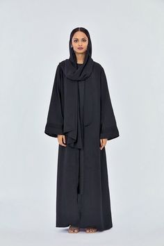 Kayfi Breezy Shawl Abaya In Midnight Black 

When she heads out, she never leaves style behind. When she dons this cover-up, she's luxed-up & ready to go.
Her elegance is eternal, as she likes it. Add a little 70s flair with this midnight black abaya. The abaya opens down the front with a dramatic shawl collar. The dropped shoulders & the flared full-length sleeves harken back luxe loungewear. In this maxi-length abaya, you simply cannot go wrong.
This abaya comes with a matching headscarf Beautiful Abayas, Fashion Abaya, Abaya Online, Luxe Loungewear, Black Abaya, Open Abaya, Bridal Lehenga Red, Abaya Designs, Midnight Black