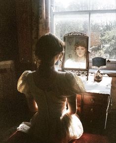 a woman sitting in front of a window looking out at a child's face