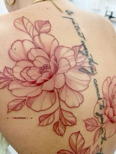 the back of a woman's shoulder with flowers and words tattooed on her arm