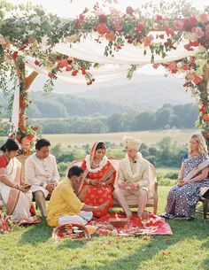 a group of people sitting on top of a lush green field next to each other