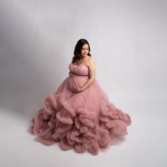 a pregnant woman in a pink gown posing for a photo with her hands on her hips