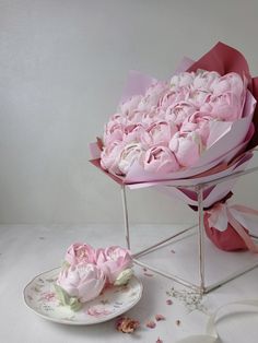 a bunch of pink flowers sitting on top of a table next to a white plate