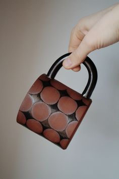 a hand is holding a brown and black bag with circles on it's handle