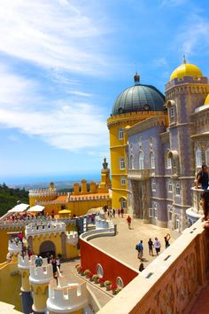 people are standing on the top of a building with yellow and white architecture in front of blue sky