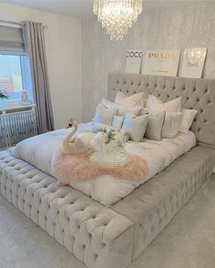 a large bed with pillows and blankets on it in front of a chandelier