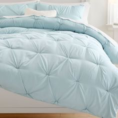 a bed with blue comforter and pillows on it