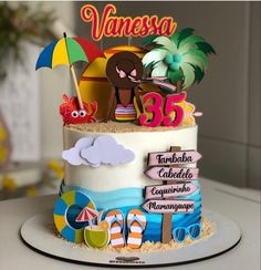 a decorated birthday cake with an umbrella and beach scene on it's top tier