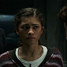 a woman in a sweater looking at another person with an evil look on her face