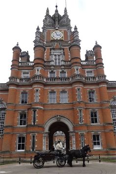 a horse drawn carriage in front of a large building with a clock on it's face