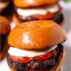 several hamburgers with cheese and tomatoes on them