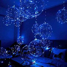 some blue lights are hanging from the ceiling above a bed in a room with black walls