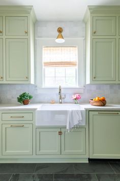 a kitchen with green cabinets and white counter tops, along with a gold faucet