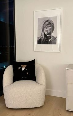 a black and white photo hangs on the wall next to a chair with a pillow