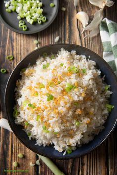 white rice with green onions in a black bowl