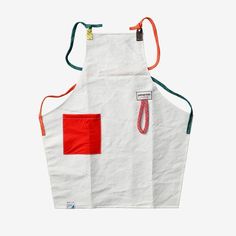 a white apron with red and green accents on it, hanging from a hook in front of a white background