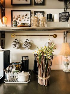 a kitchen counter with coffee cups and mugs on the shelf above it, along with other items