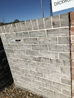 a brick wall with a sign that says brickwork on it and gravel in the foreground