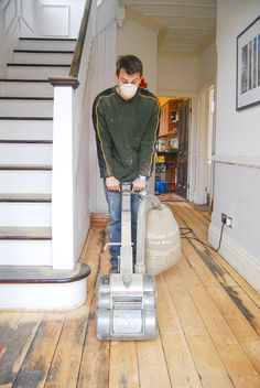 a man with a face mask is using a vacuum to clean the floor in his house