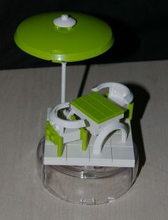 a green and white plastic chair sitting on top of a table next to a lamp