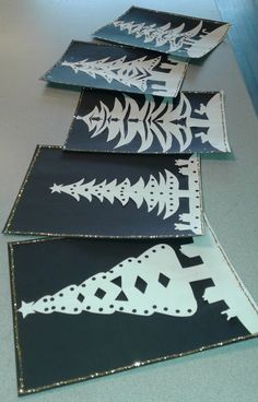 four black and white paper cut outs with designs on them sitting on top of a table