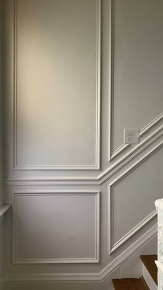 an empty room with white painted walls and wood flooring on the bottom half of the stairs