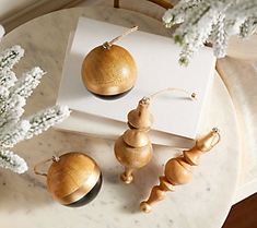 three wooden ornaments sitting on top of a marble table next to white flowers and branches