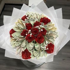 a bouquet made out of dollar bills and red roses